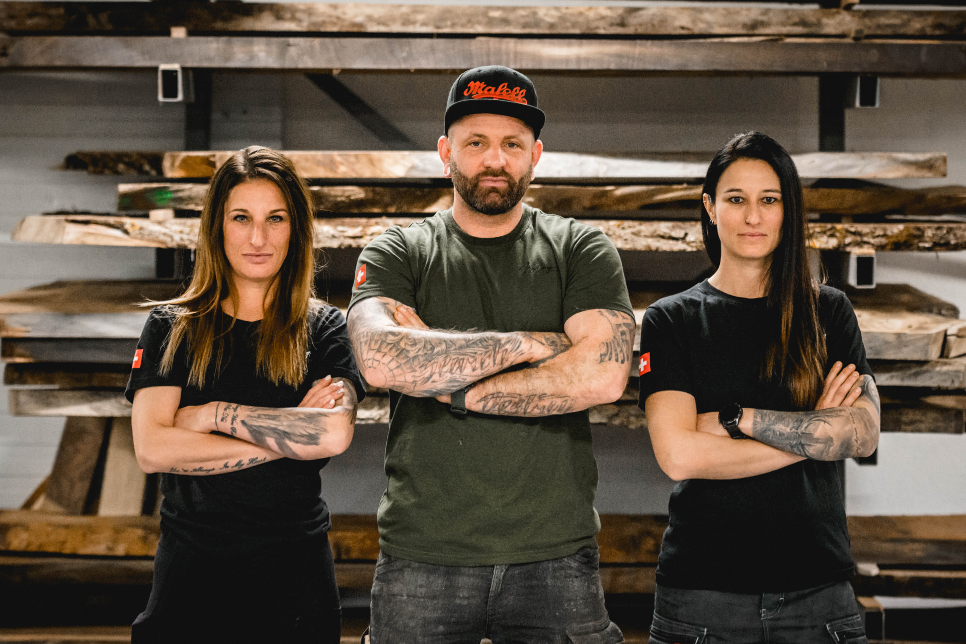 Team von Jungo Design in der Werkstatt vor Holzbohlen
